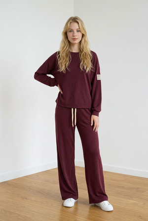 Completo tuta composto da felpa girocollo a maniche lunghe con spalla scesa, con dettaglio patch sulla manica, e pantalone a gamba dritta. Il pantalone ha elastico in vita, coulisse regolabile a contrasto e pratiche tasche laterali.