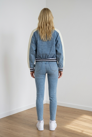 Giubbino stile college, realizzato in denim leggero. Il modello presenta chiusura frontale con bottoni a pressione e scritta sul davanti; le maniche sono a contrasto, i polsini, il colletto e i bordi, elasticizzati a righe, richiamano il classico stile sportivo americano.