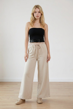 Pantalone palazzo beige,con vita elasticizzata in fantasia scozzese. Il cordino regolabile richiama il motivo della cintura elasticizzata. La gamba ampia slancia la figura.