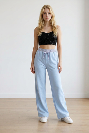 Pantalone palazzo, celeste, con vita elasticizzata in fantasia scozzese. Il cordino regolabile richiama il motivo della cintura elasticizzata. La gamba ampia slancia la figura.