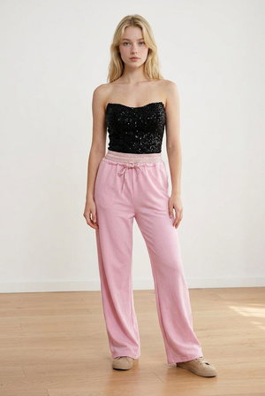 Pantalone palazzo rosa, con vita elasticizzata in fantasia scozzese. Il cordino regolabile richiama il motivo della cintura elasticizzata. La gamba ampia slancia la figura.