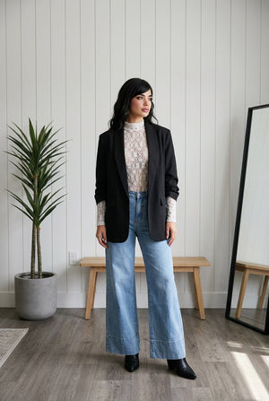 Jeans palazzo indossato in denim chiaro high-waist con fondo ampio e risvolto strutturato, tasche posteriori con applicazioni rosa brillanti