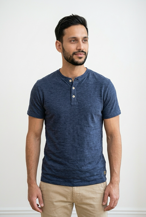 T-shirt maniche corte realizzata con tessuto effetto crepe. Il modello presenta una chiusura frontale con 3 bottoni a contrasto e girocollo con apertura. Sul fondo, a sinistra, una piccola targhetta decorativa in legno.