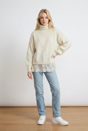 Vestito crema realizzato in morbida maglia calda, con maniche lunghe e ampio collo avvolgente con lavorazione a costine, coordinato al fondo a costine. Dettaglio la balza inferiore in pizzo.