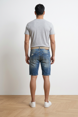 Bermuda denim uomo in cotone con vestibilità slim comfort e lunghezza al ginocchio. Lavaggio stone wash medio con effetto used, rotture e abrasioni frontali