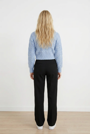 Cardigan CROP grigio chiaro in maglia lavorata con raffinato motivo traforato a onde. Il design presenta uno scollo a V, chiusura frontale con 5 bottoni tono su tono e maniche lunghe con polsini e coste. 