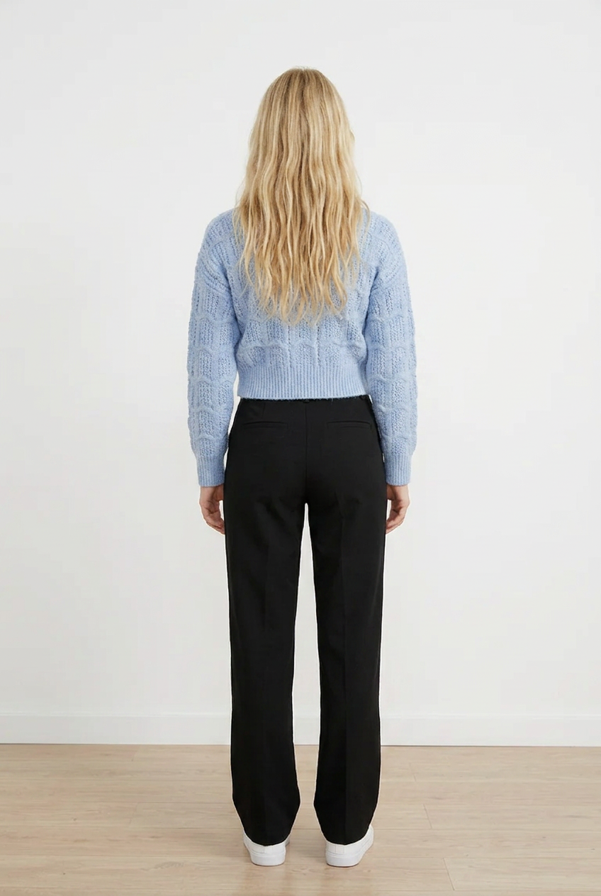 Cardigan CROP grigio chiaro in maglia lavorata con raffinato motivo traforato a onde. Il design presenta uno scollo a V, chiusura frontale con 5 bottoni tono su tono e maniche lunghe con polsini e coste. 