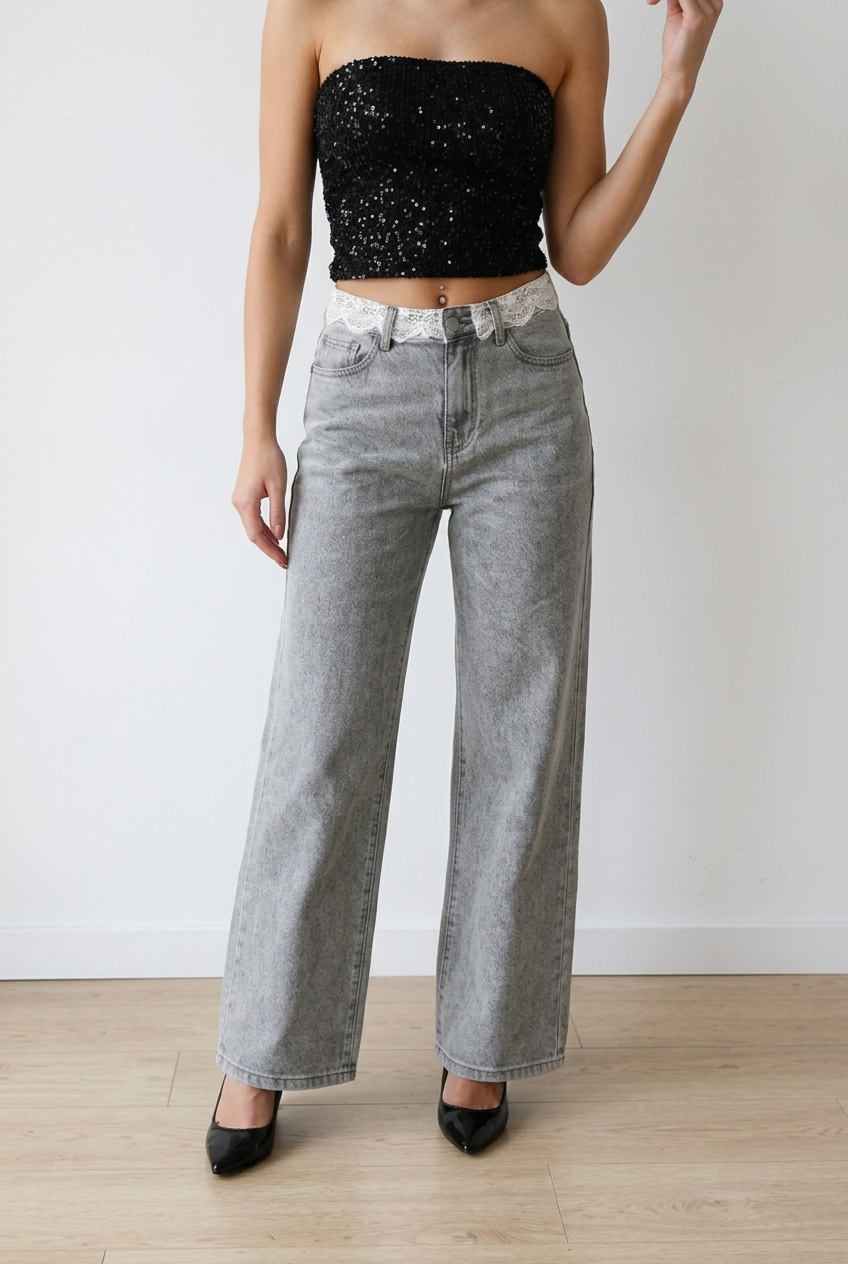 Jeans palazzo in denim grigio effetto slavato. La vita alta valorizza la silhouette, mentre la gamba ampia e dritta slancia la figura. Il pizzo lungo il punto vita, aggiunge un elemento femminile e ricercato. 
