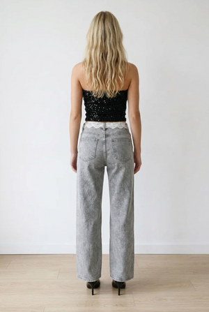 Jeans palazzo in denim grigio effetto slavato. La vita alta valorizza la silhouette, mentre la gamba ampia e dritta slancia la figura. Il pizzo lungo il punto vita, aggiunge un elemento femminile e ricercato. 
