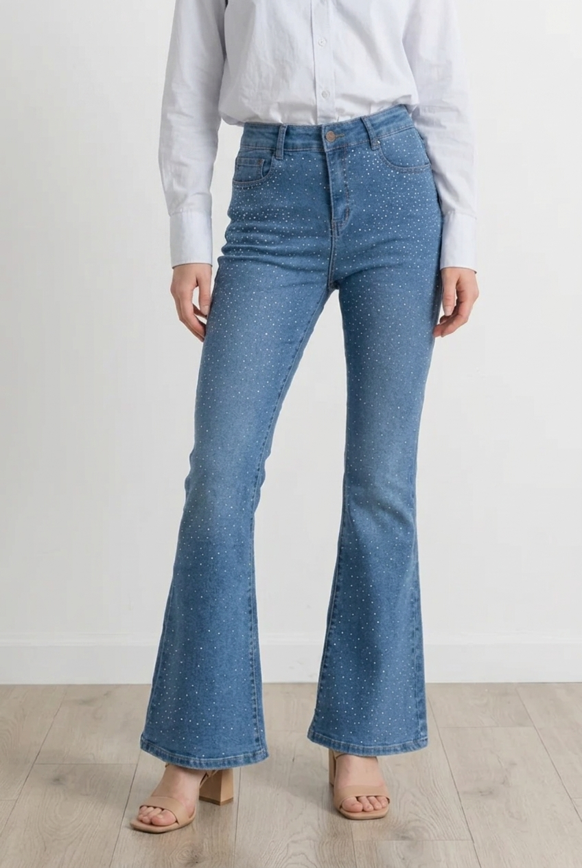 Jeans flare in denim chiaro, modello high-waist che valorizza il punto vita e slancia la figura. Questo capo d'abbigliamento segue la linea dei fianchi per poi aprirsi in una gamba a zampa, creando un effetto sinuoso ed elegante; il tessuto è impreziosito da micro applicazioni brillanti effetto sparkling distribuite su tutta la parte frontale.