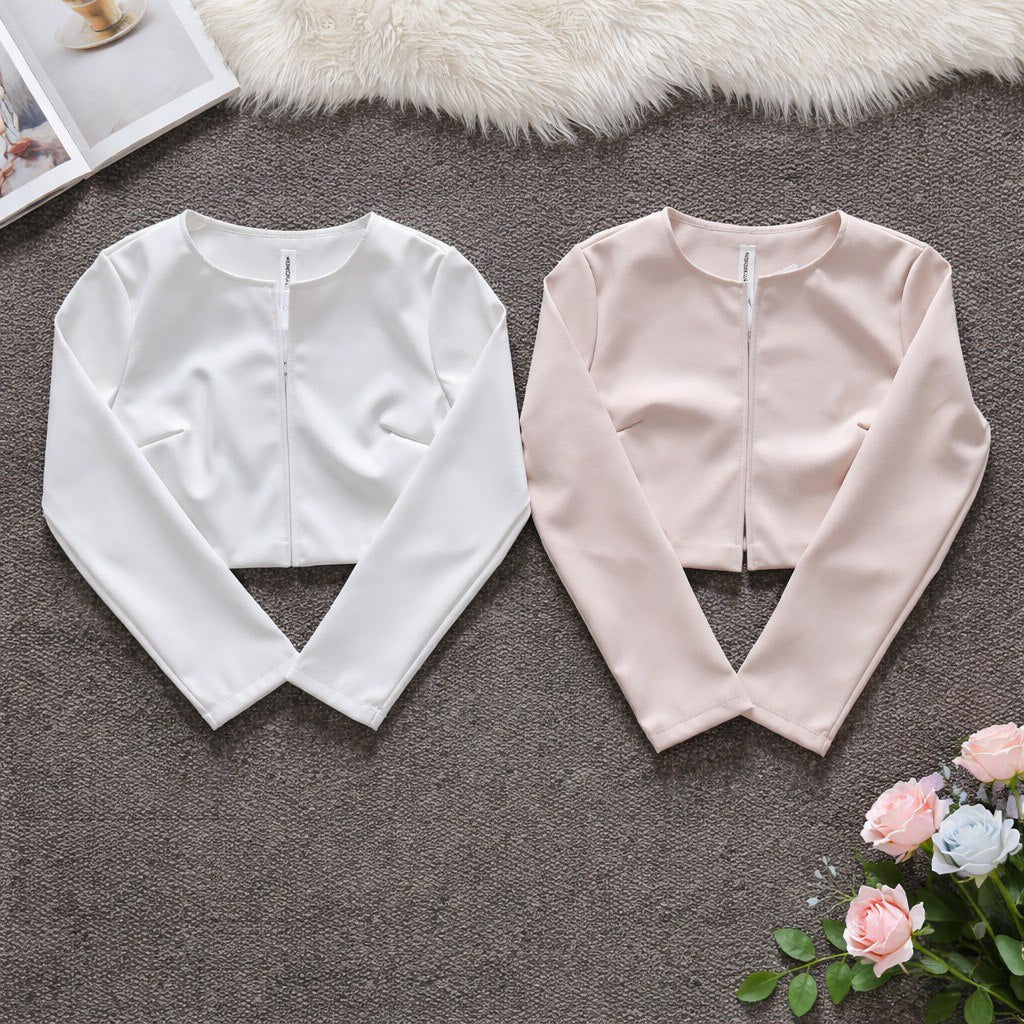 Giacca cropped beige e bianca senza colletto in ecopelle indossata, vestibilità cota e struttura minimal, vista frontale