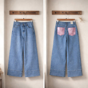 Jeans palazzo in denim chiaro high-waist con fondo ampio e risvolto strutturato, tasche posteriori con applicazioni rosa brillanti, vista frontale e posteriore