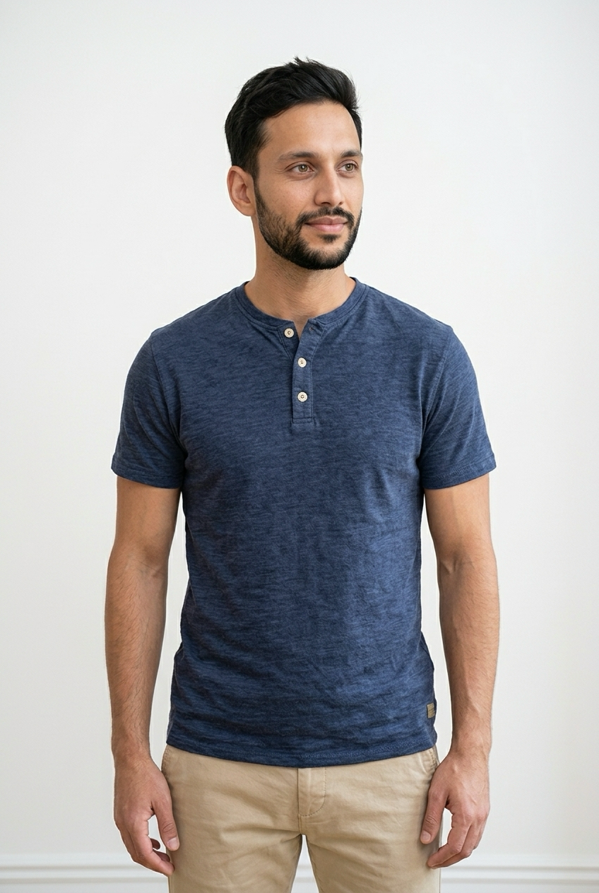 T-shirt maniche corte realizzata con tessuto effetto crepe.  Il modello presenta una chiusura frontale con 3 bottoni a contrasto e girocollo con apertura. Sul fondo, a sinistra, una piccola targhetta decorativa in legno. 
